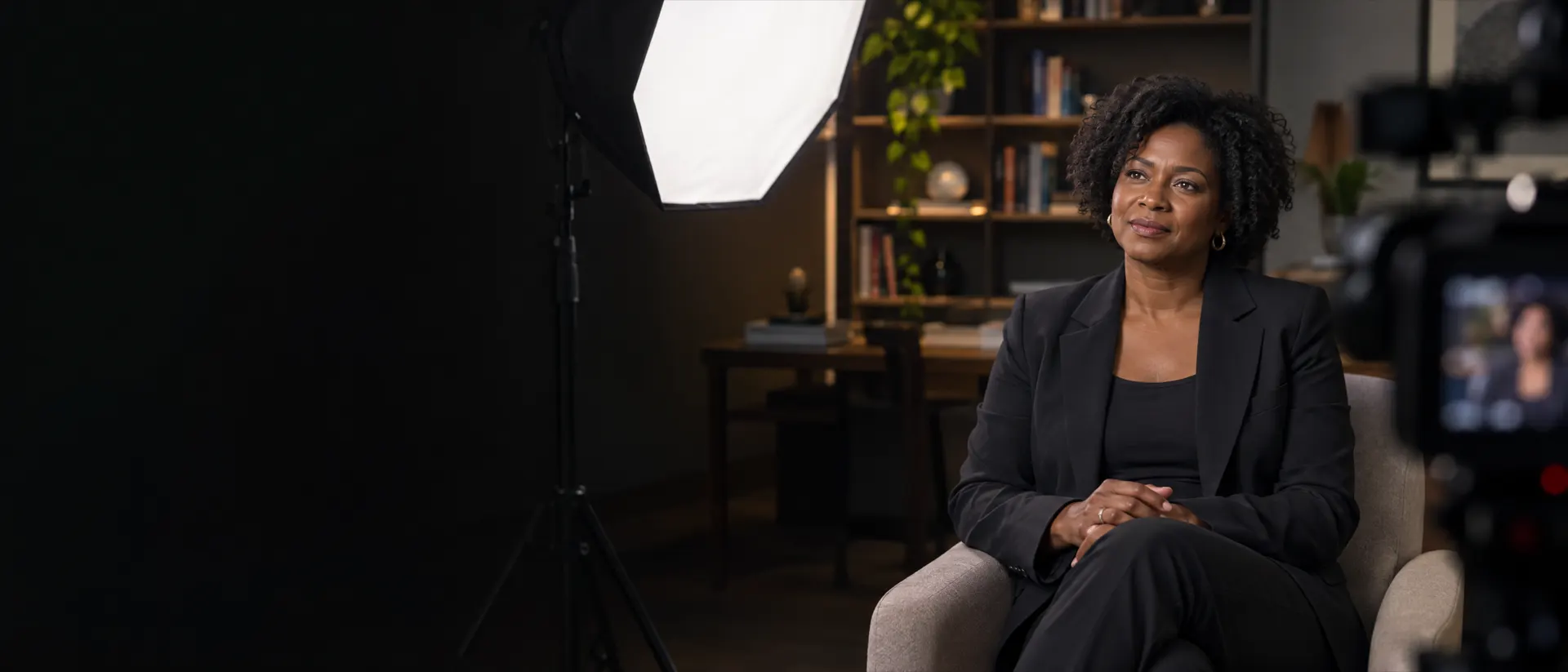 Entrevistada sentada numa poltrona, iluminada por um softbox grande num tripé de iluminação