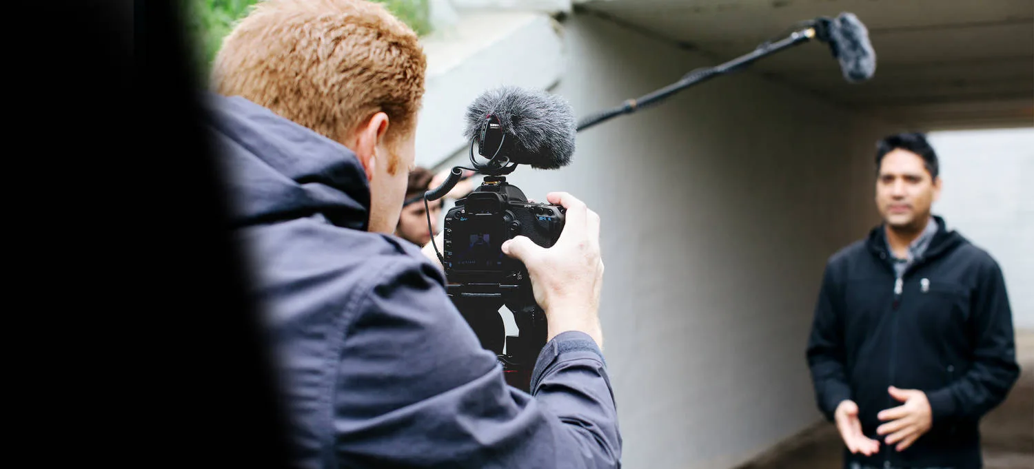 Cinegrafista gravando entrevista na rua com microfone Shure montado na câmera